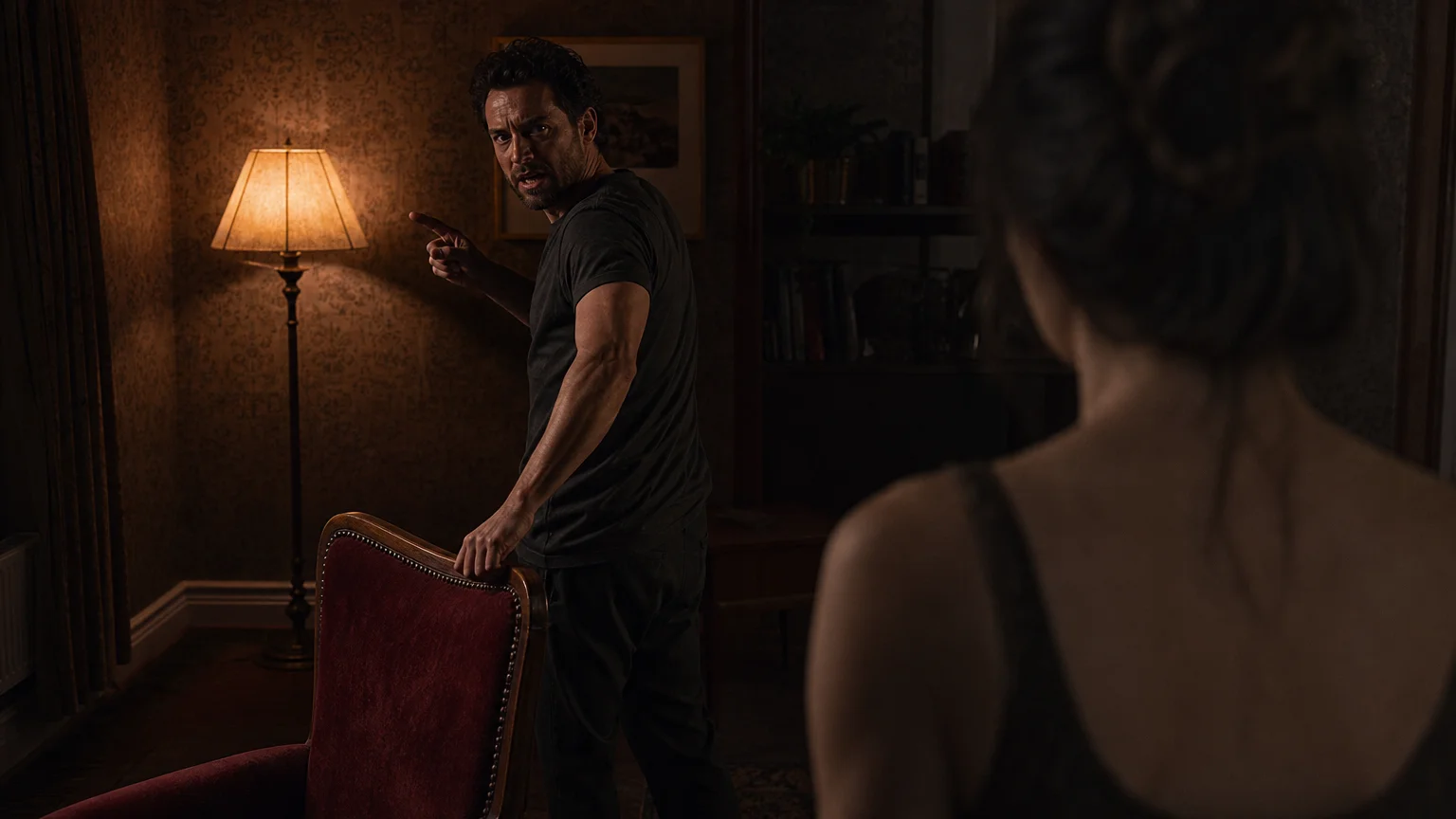 A photo of a man reacting defensively during an argument in a dimly lit room, his body language shifted into a sharp, accusatory stance.